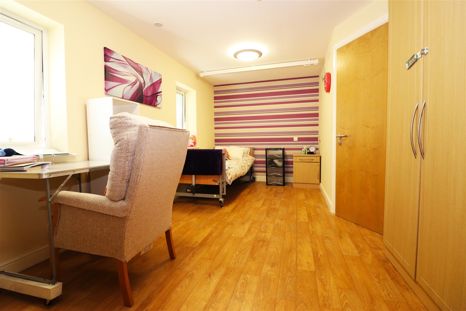 A bedroom at Queens Lodge with a striped wall and a ceiling track