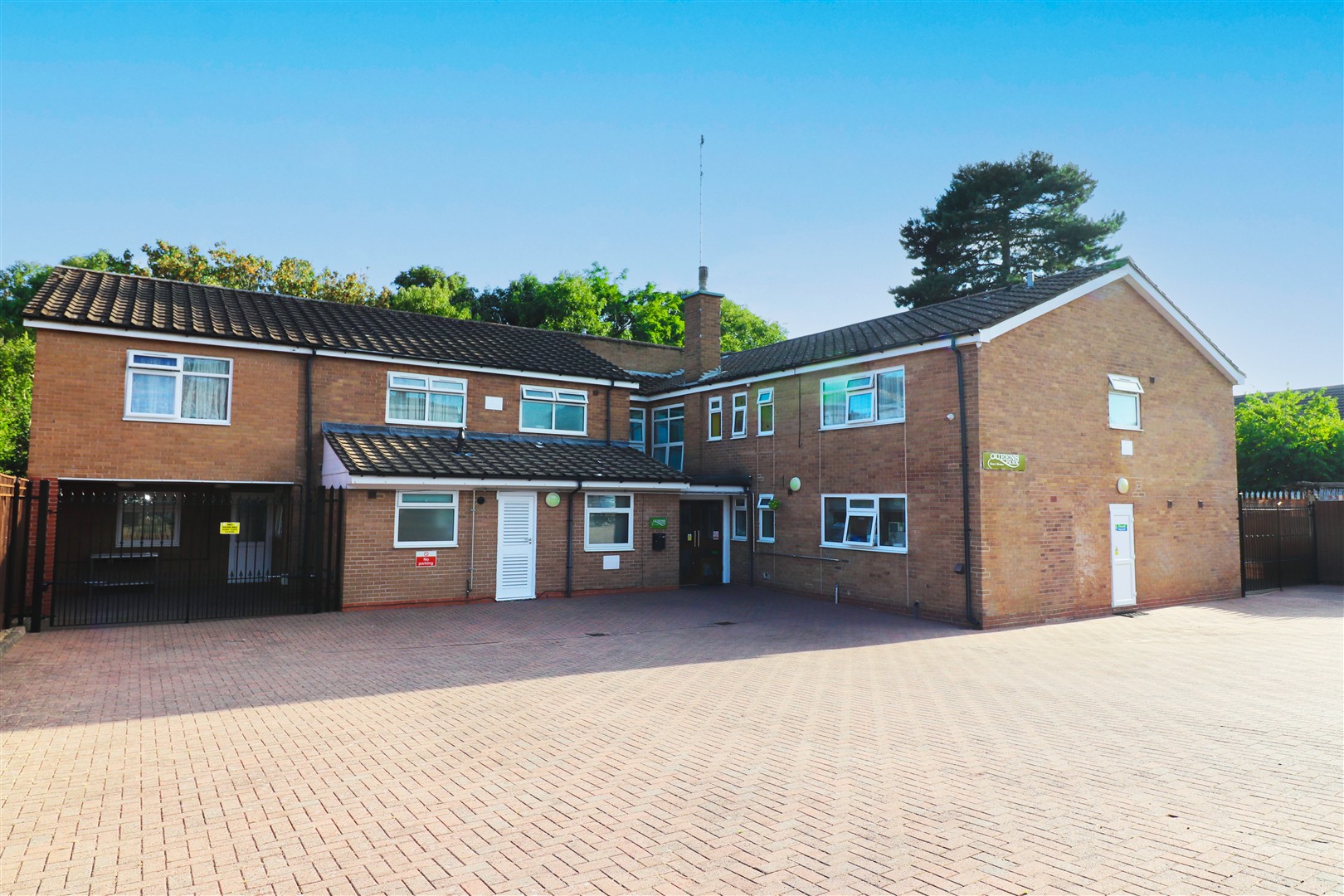 The brick front of Queens Park Care Home and its courtyard